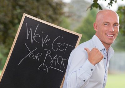 Backfit doctor poses with blackboard for fun business portrait