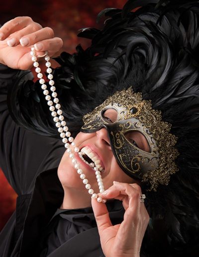 Fun and dramatic portrait of woman with mask and pearls