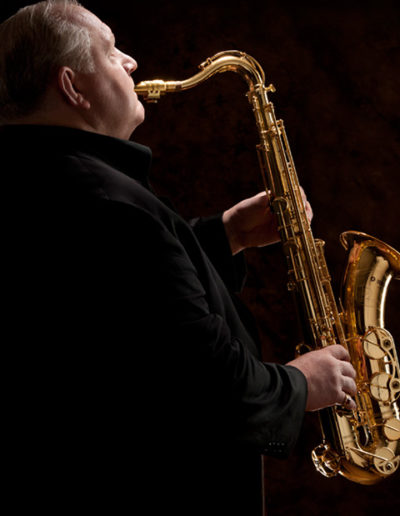 Musician plays the saxophone in dramatically lit portrait in studio