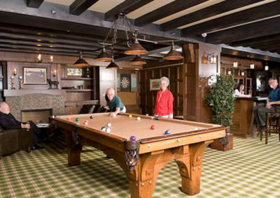 Retirees pose around pool table in on location portrait