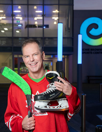 Hockey player poses with equipment outside of rec center for professional headshot